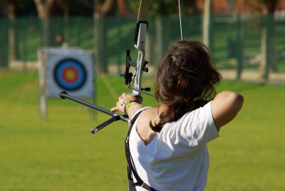 Back of archery athlete aiming at a target in the distance