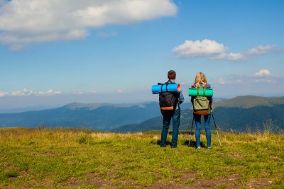 Backpacker couple standing on hill looking at sky