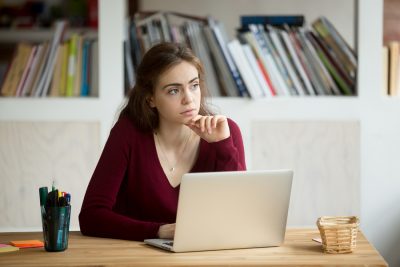 Thoughtful young female business owner in front of laptop. 
